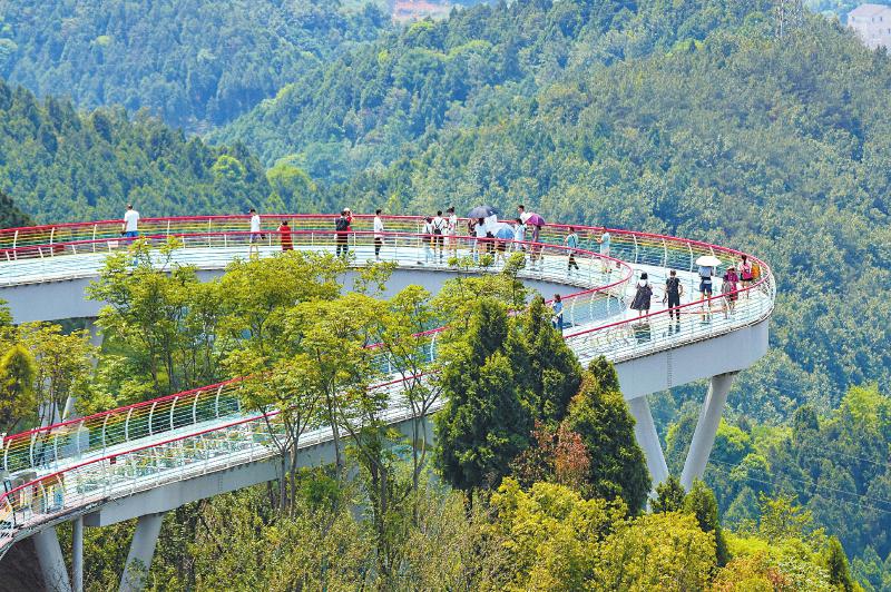 6月15日,游客在成都市龙泉山城市森林公园的丹景台上俯瞰城市美景.