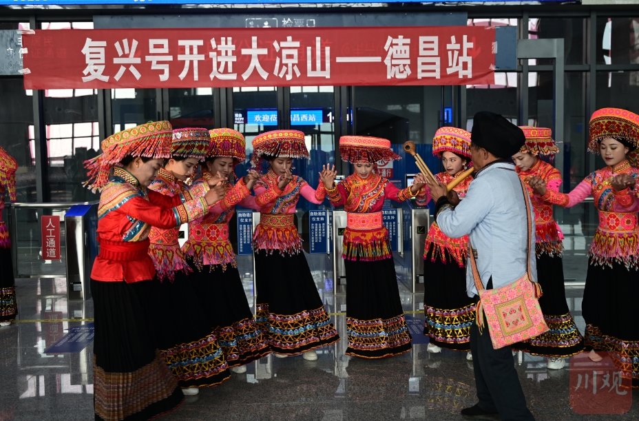 在德昌西站,一队傈僳族同胞身着华丽的民族服饰,载歌载舞迎接动车开进