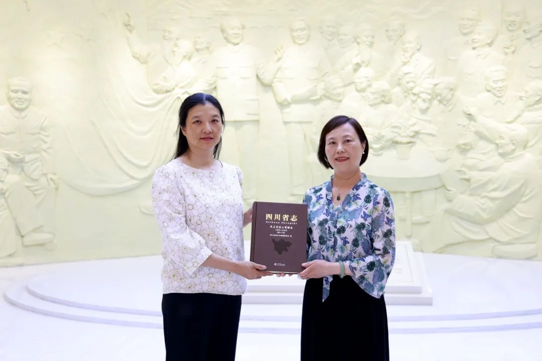 四川省地方志办党组成员、副主任、机关党委书记邓瑜（左）向四川省社会主义学院二级巡视员向阳赠送《四川省志·民主党派工商联志》.jpg
