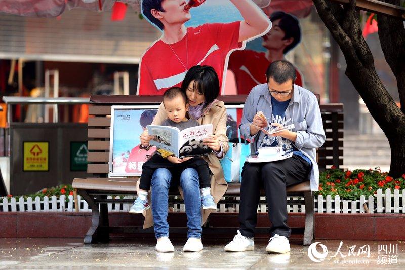 2019年9月28日，春熙路，领取书籍后的群众便兴趣盎然的阅读起来。（图片由四川省地方志工作办提供）